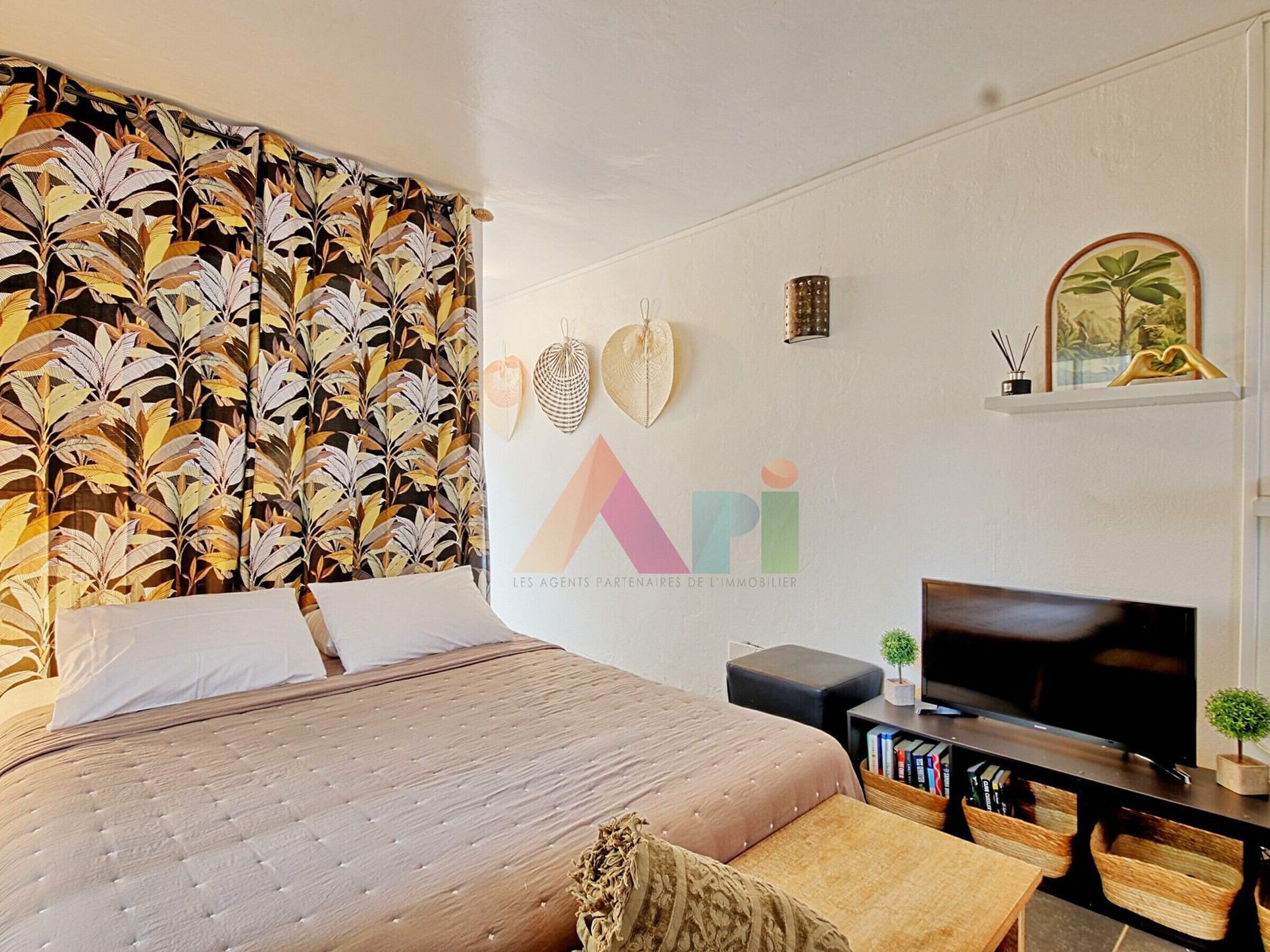 A bedroom with a large bed, a TV, and a bookshelf.