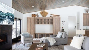 A modern living room with a fireplace, grey sofas, a coffee table, and a wooden cabinet with shelves.
