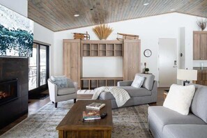 A modern living room with a fireplace, grey sofas, a coffee table, and a wooden cabinet with shelves.