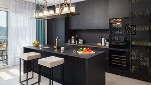 Una cocina moderna con una isla central, taburetes de bar, horno empotrado y vistas al exterior.
