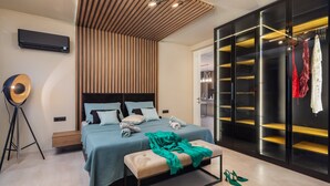 Un dormitorio moderno con cama, mesita de noche, banqueta y un vestidor con estantes.