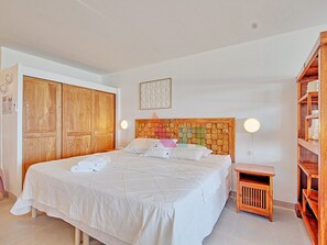 A bedroom with a bed, wooden wardrobe, bedside table, and a shelf unit. - Studio with Pool in Saint-Martin (Saint-Martin)