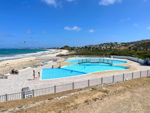 A swimming pool with a beach view, surrounded by a fence and lounge chairs. - Studio with Pool in Saint-Martin (Saint-Martin)