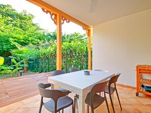 An outdoor patio with a table and chairs, surrounded by a garden with various plants and a fence. - Villa Coquelicot - 2 Bedrooms, Beach and Garden (Saint-Martin)