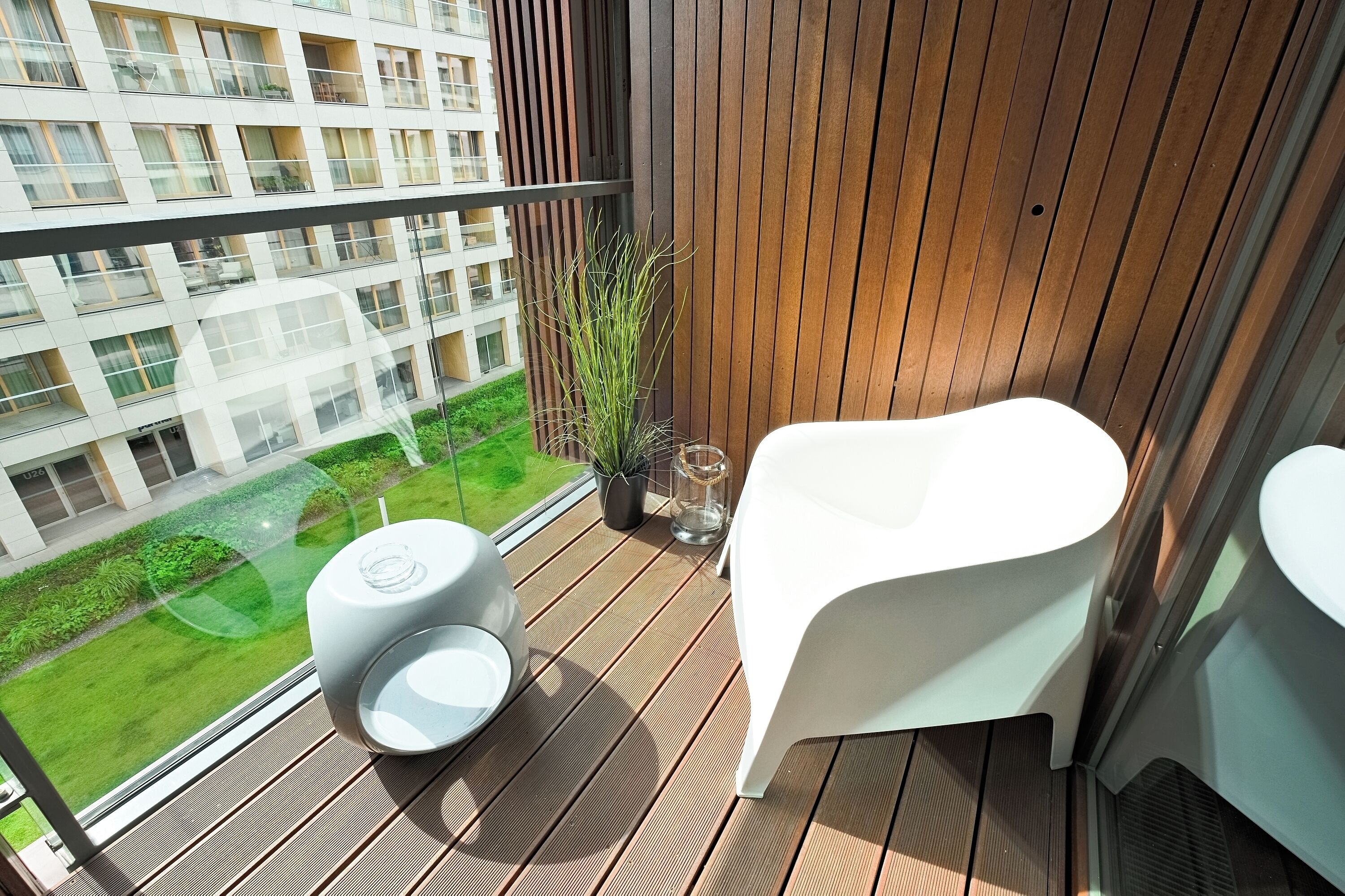 A balcony with a white chair, a small table, and a potted plant.