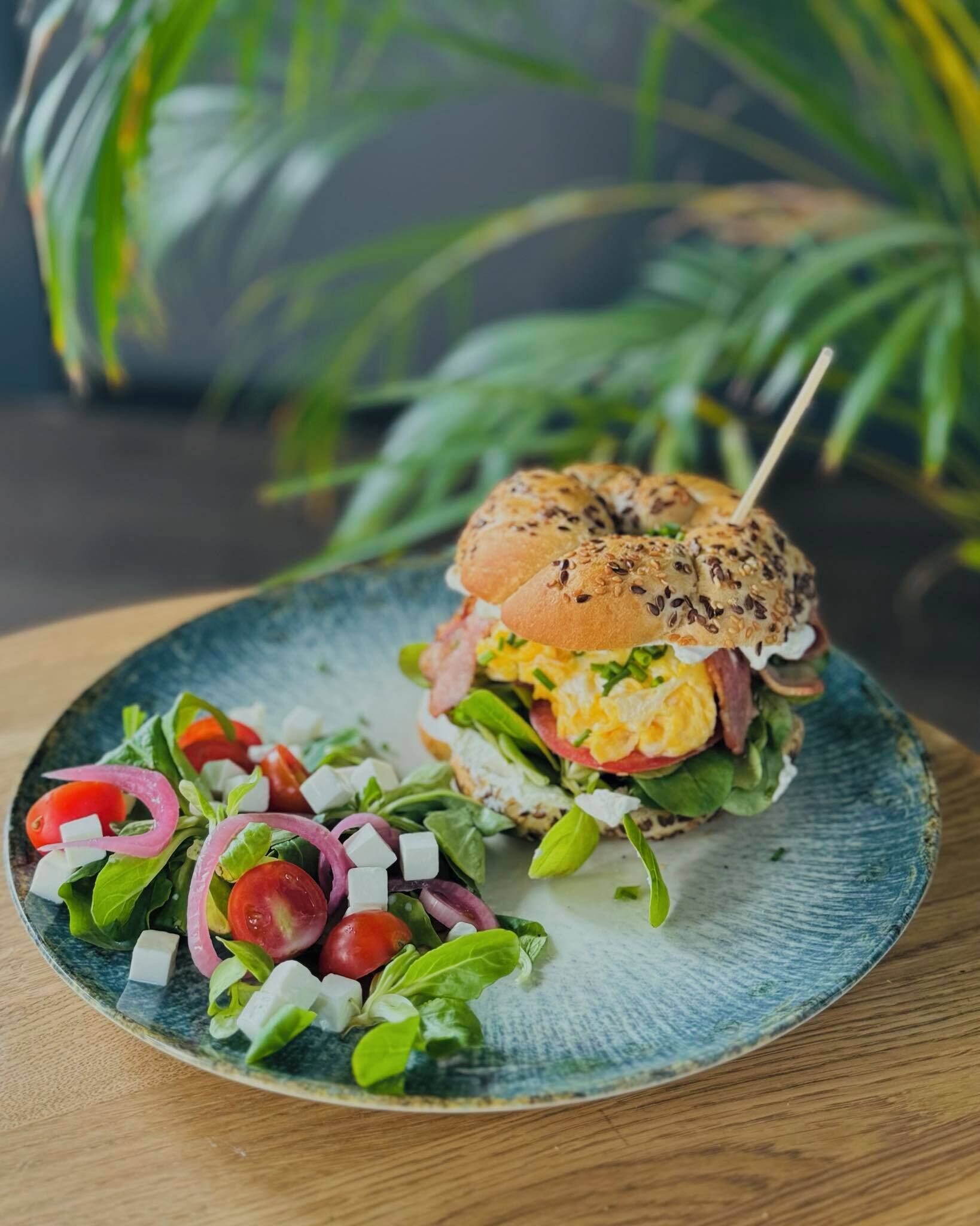 Un sándwich en un plato acompañado de una ensalada.