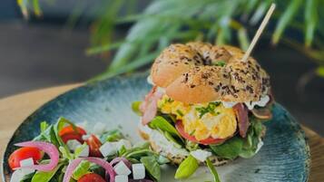 Un sándwich en un plato acompañado de una ensalada.