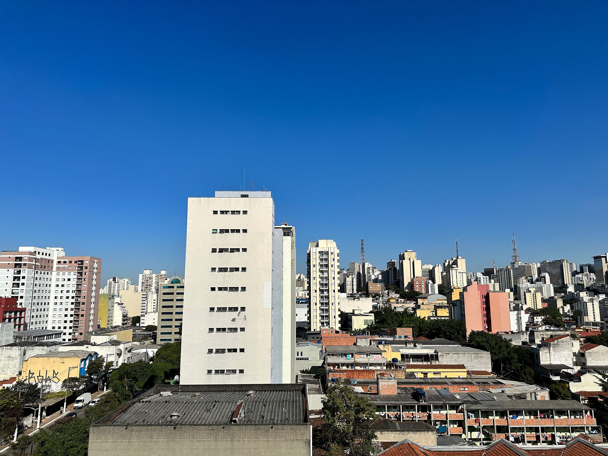 A cityscape with a prominent white building in the foreground and a dense cluster of buildings in the background.