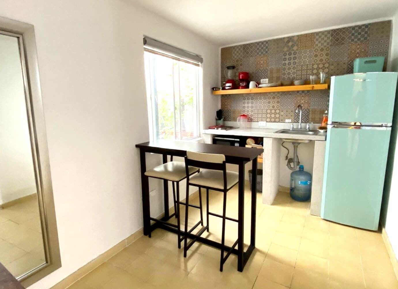 Una cocina compacta con refrigerador, pileta y ventana.