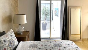 A bedroom with a bed, a lamp, a wardrobe, and a sliding glass door to the outside. - Villa Esterito (La Paz)