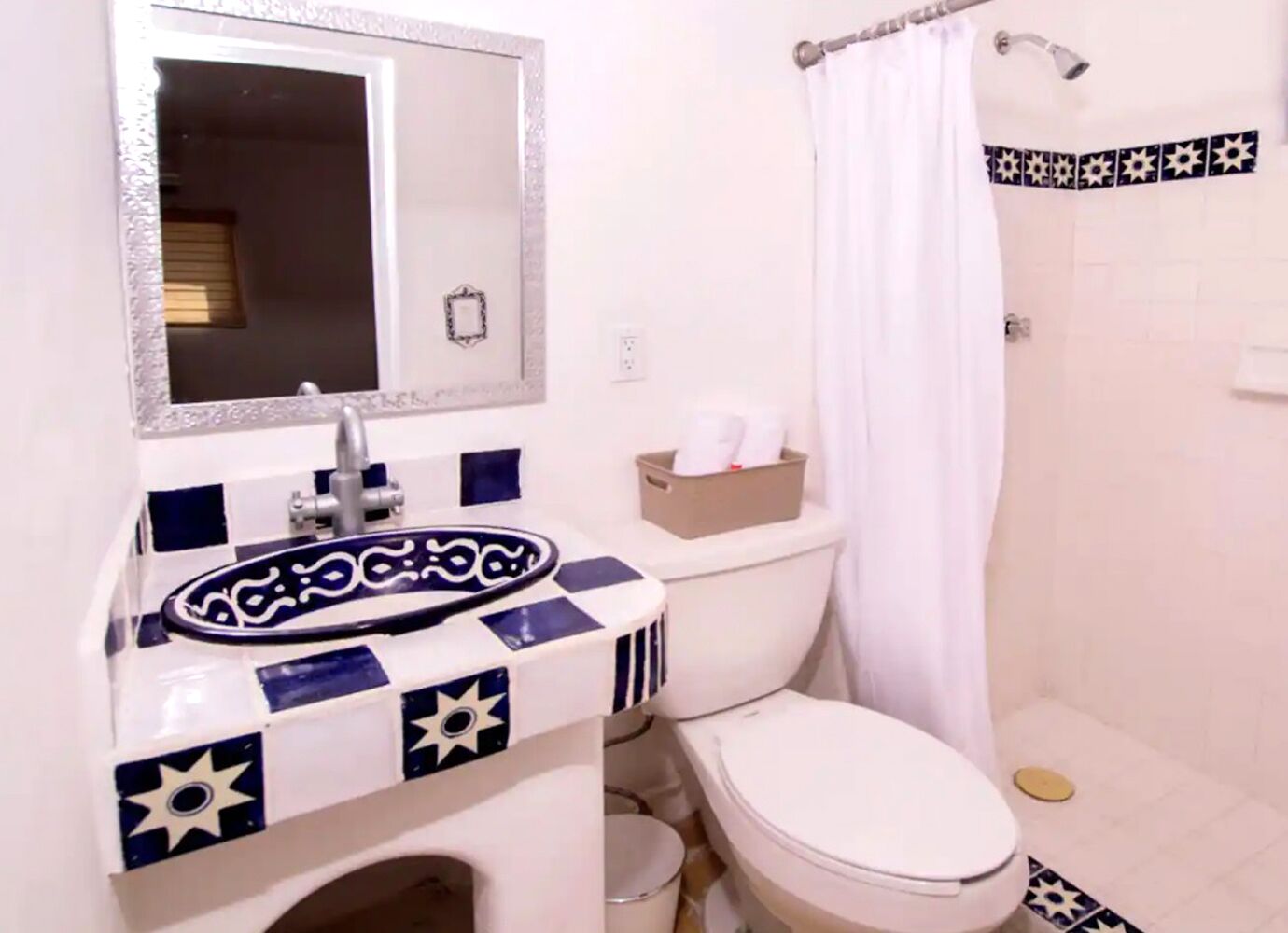 Ein Badezimmer mit Waschbecken, Spiegel, Toilette und Duschvorhang.