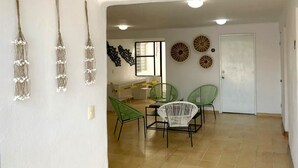 A dining area with a table and chairs, a white door, and wall decorations. - Villa Esterito (La Paz)