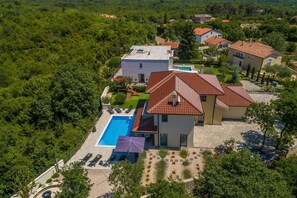 Vista aérea de um bairro residencial com casas, piscina e jardim.