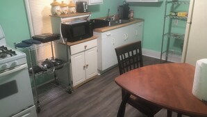A compact kitchen with a stove, microwave, sink, and a dining table with chairs. - Nice little hideaway close to all the downtown amenities  (Fort Wayne)
