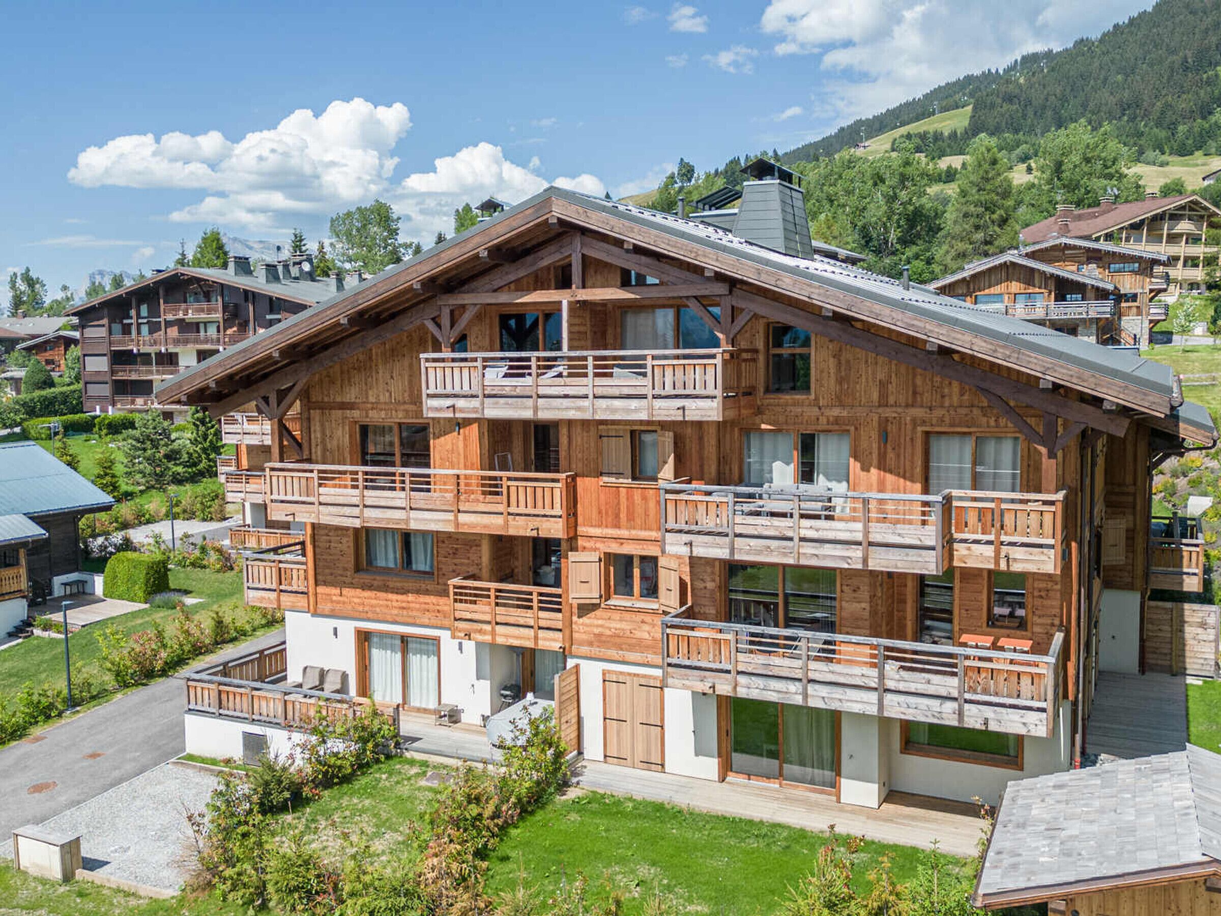 Een houten chalet met meerdere verdiepingen en balkons, gelegen in een bergachtig gebied.