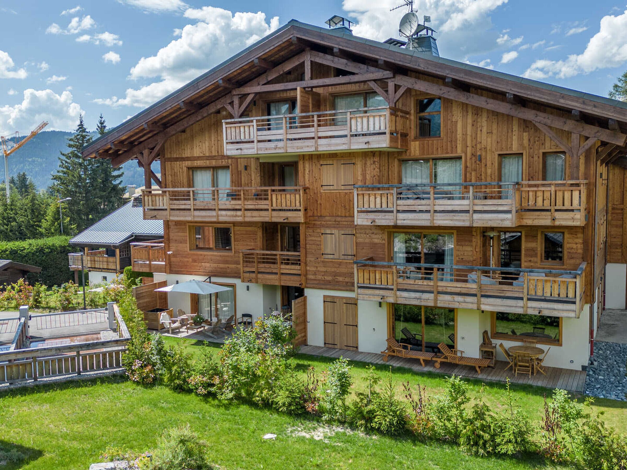Eine mehrstöckige Holzhütte mit Balkonen, einer Terrasse mit Gartenmöbeln und Blick auf die umliegende Landschaft.