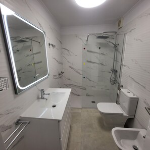 A modern bathroom with a marble backsplash, a large mirror, a shower, a toilet, and a sink. - San Marino 5 (Los Cristianos)