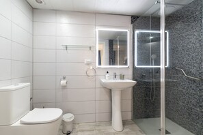 Une salle de bain moderne équipée de toilettes, d’un lavabo et d’une douche.
