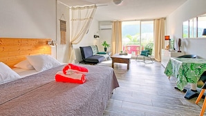 A hotel room with a bed, a desk, a chair, a balcony with a table, and a view of the outdoors. - Comfortable Studio with Pool and Wi-Fi Near Beach (Saint-Martin)
