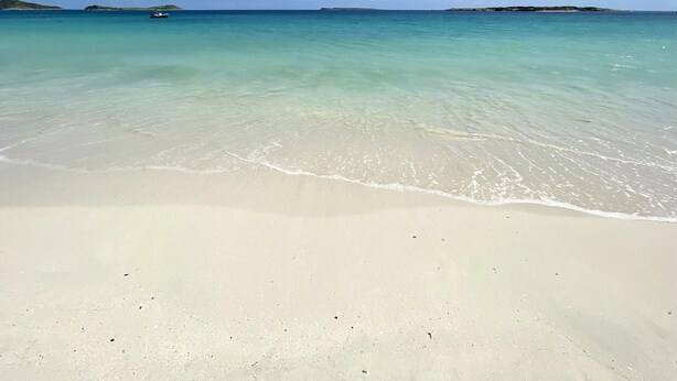 A beach with clear turquoise water and a boat in the distance. - Comfortable Studio with Pool and Wi-Fi Near Beach (Saint-Martin)