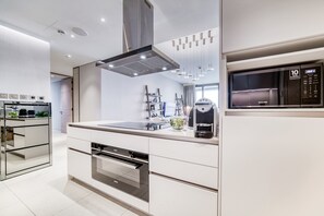 A modern kitchen with a built-in oven, a coffee machine, and a microwave.