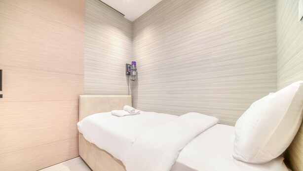 A modern hotel room with a bed, a wall-mounted water dispenser, and a tiled floor. - Picturesque Balcony and Beach Haven at Address JBR (Dubai)