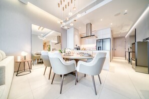 A modern kitchen with a dining area, featuring a large island, contemporary lighting, and a clean, minimalist design.