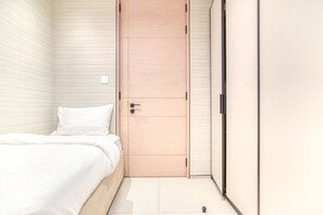 A bedroom with a bed, a wooden door, and a wardrobe.