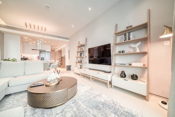 A modern living room with a sofa, coffee table, TV, and built-in shelves.