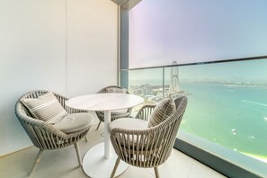 A balcony with wicker furniture and a view of a cityscape and water.