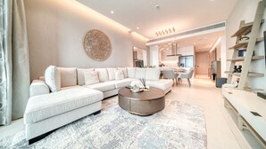 A modern living room with a sectional sofa, a round coffee table, and a decorative wall piece. - Picturesque Balcony and Beach Haven at Address JBR (Dubai)