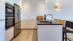 Ett modernt kök med rostfria vitvaror, en inbyggd ugn och en stor köksö med en diskho.