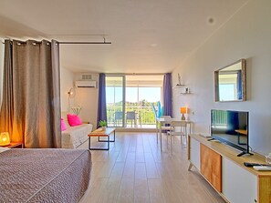 A hotel room with a bed, a desk, a TV, and a balcony with a view. - Spacious Studio in Saint Martin with Terrace and Equipped Kitchen (Saint-Martin)