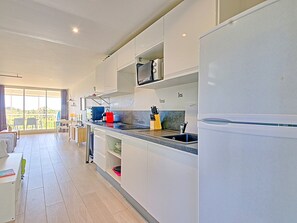 A modern kitchen with white cabinets, a black countertop, and a stainless steel sink.