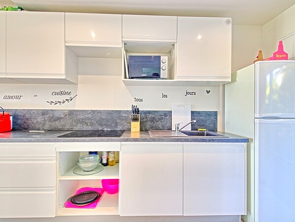 A modern kitchen with white cabinets, a microwave, a sink, and a refrigerator. - Spacious Studio in Saint Martin with Terrace and Equipped Kitchen (Saint-Martin)