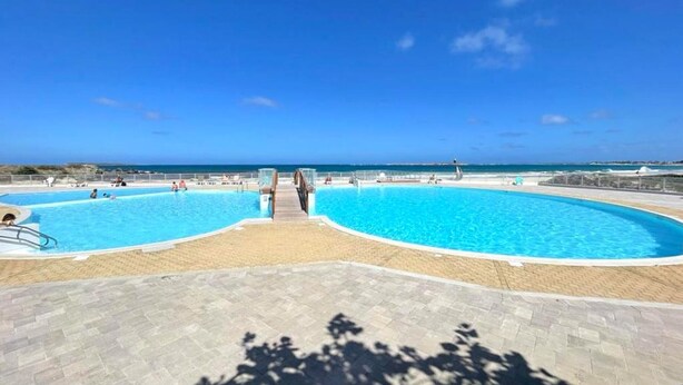 Ein großer Pool im Freien mit Holzterrasse und Meerblick.
