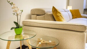 A living room with a beige sofa, a glass coffee table, and a green plant. - Lakeside (Como)