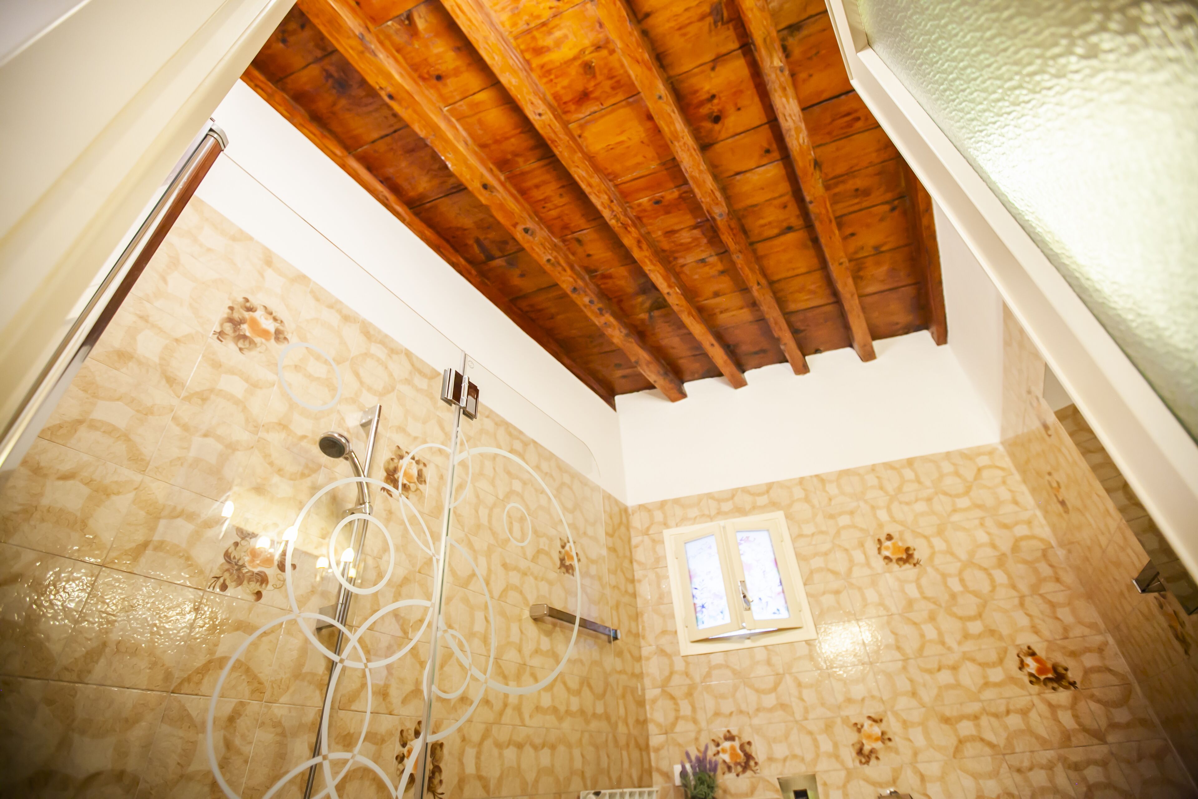 Une salle de bain avec un plafond en bois, des murs à motifs et un espace douche.