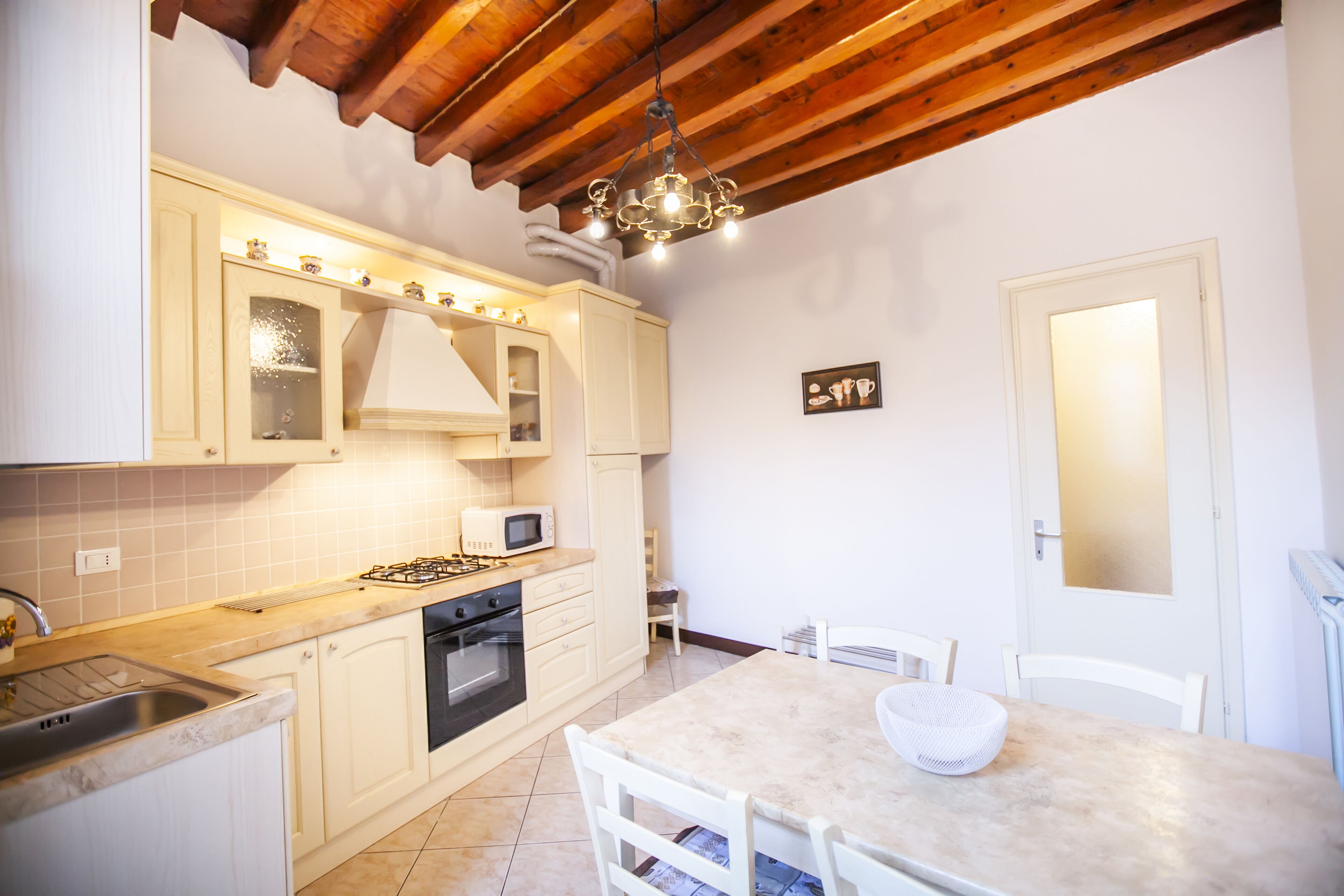 A kitchen with white cabinets, a microwave, a gas stove, and a chandelier.