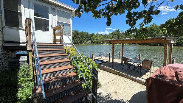 A deck with outdoor furniture, a covered seating area, and a view of a lake.
