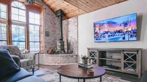Una sala de estar acogedora con chimenea, un sofá cómodo y un cuadro grande de un pueblo nevado.