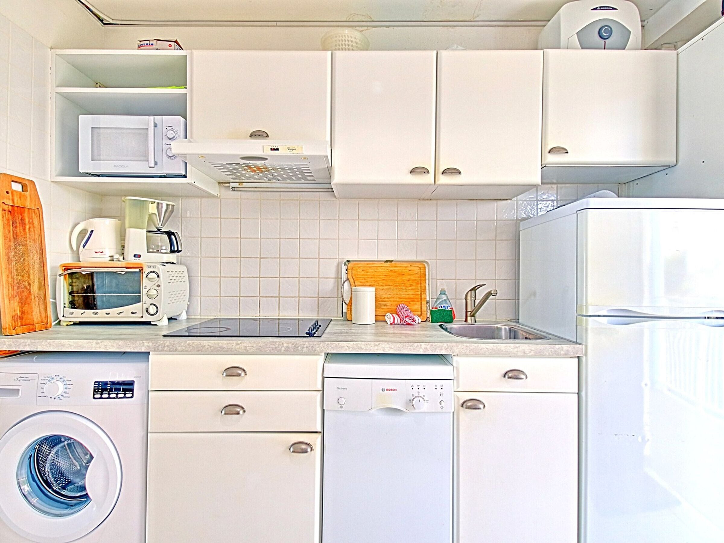 Een kleine keuken met een magnetron, broodrooster, koffiezetapparaat, spoelbak en vaatwasser.