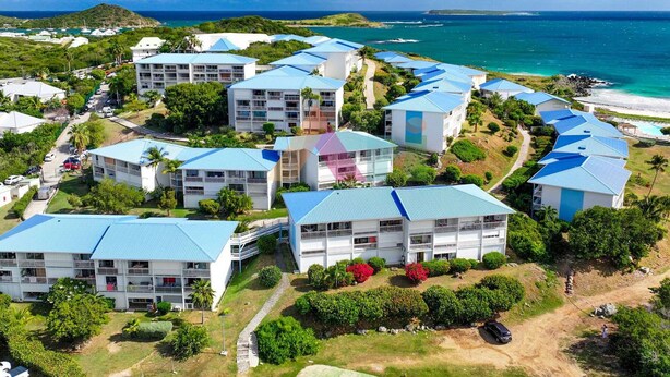 A resort with multiple buildings featuring blue roofs, arranged around a central area with a view of the ocean. - Spacious Studio with Ocean View and Pool (Saint-Martin)