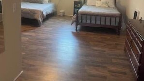 A small attic bedroom with two beds, a wooden floor, and a sloped ceiling.