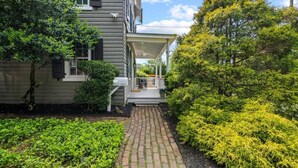 A house with a covered porch, a brick pathway, and lush greenery. - Historic Home Central Flourtown Hosted By StayRafa (Flourtown)