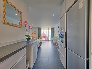 Una cocina moderna con refrigerador empotrado, una encimera con planta en maceta y vista al área de comedor.