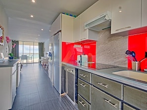 A modern kitchen with a red backsplash, stainless steel appliances, and a view to the outside. - Orchidée Studio at Mont Vernon with views of Orient Bay (Saint-Martin)