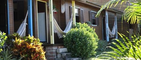 A wooden house with a porch, a hammock, and a well-maintained garden.