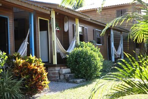 A wooden house with a porch, a hammock, and a well-maintained garden.