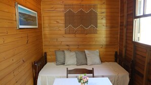 Una habitación de cabaña de madera con una cama, una mesa con un jarrón de flores y un cuadro en la pared.